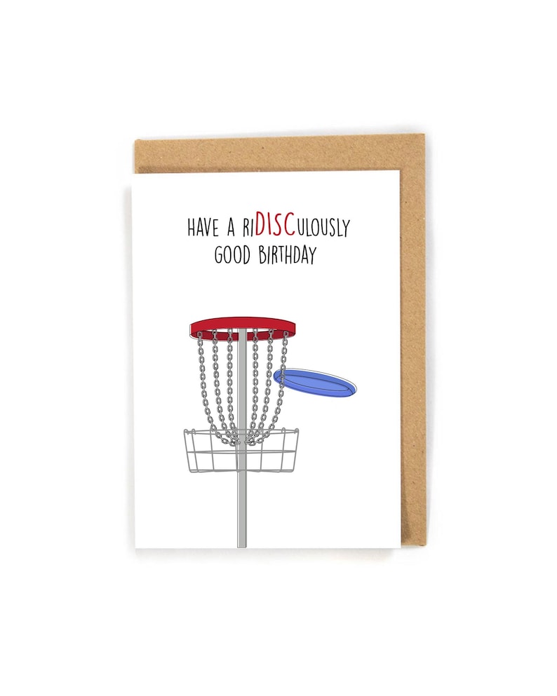 Peut inclure: Carte d'anniversaire avec une enveloppe marron. La carte pr&eacute;sente un panier de disc golf rouge et argent&eacute; avec un disque bleu. Le texte dit "Have a Ridiculously Good Birthday" en rouge et noir.