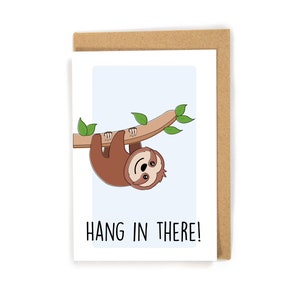 May include: A greeting card with a cartoon sloth hanging upside down from a branch. The card has a light blue background and the text "HANG IN THERE!" in black.