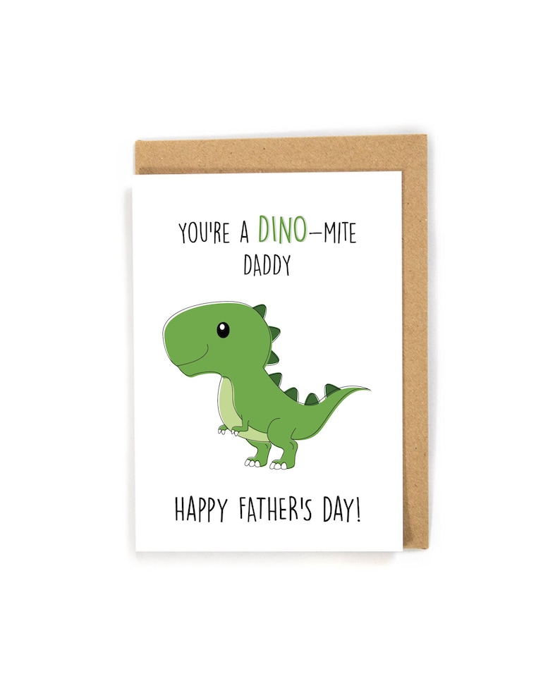 May include: A white card with a green dinosaur illustration and the text "You're a Dino-mite Daddy Happy Father's Day!"