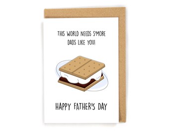 May include: A Father's Day card with a brown kraft paper envelope. The card features a cartoon s'more with the text "THIS WORLD NEEDS S'MORE DADS LIKE YOU!" and "HAPPY FATHER'S DAY" in black font.