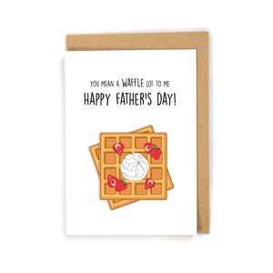 May include: A Father's Day card with a waffle illustration. The card reads "YOU MEAN A WAFFLE LOT TO ME HAPPY FATHER'S DAY!". The waffles are decorated with strawberries and cream, set against a white background.
