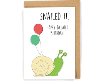 May include: A white card with a green snail carrying two balloons, one red and one green. The card says "SNAILED IT. HAPPY BELATED BIRTHDAY!"