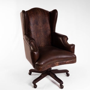 May include: A brown leather office chair with a wingback design and a swivel base. The chair has a crocodile-embossed pattern and a dark brown finish.