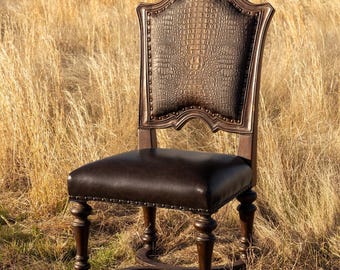 May include: A brown leather dining chair with a crocodile-embossed back and a dark brown wooden frame. The chair has a tufted seat and decorative nailhead trim.