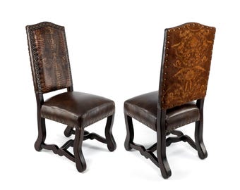 May include: Two dark brown dining chairs with leather seats and backs. One chair has a textured, patterned back, while the other features a floral design. The chairs have dark wooden frames and decorative details.