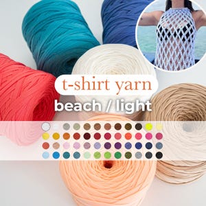 Op de afbeelding: Assortiment van t-shirt garen in verschillende kleuren, waaronder teal, rood, wit, perzik en beige. Het garen is gemaakt van gerecyclede t-shirts en is perfect voor haken of breien. Het garen is gelabeld "t-shirt garen strand/licht" en een kleurenkaart is inbegrepen.