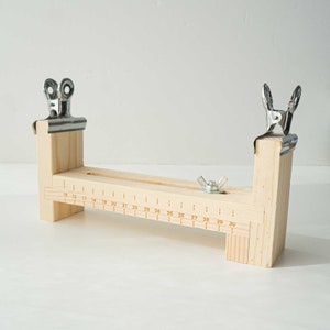 Può includere: Telaio in legno con due morsetti metallici e un righello contrassegnato da 15 a 30 pollici. Il telaio è utilizzato per la tessitura.