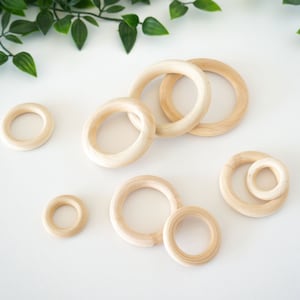 May include: A set of wooden rings of varying sizes, perfect for crafting or sensory play. The rings are natural in color and have a smooth, polished finish.