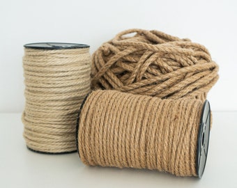 May include: Two spools of natural brown twine, one in a black plastic container and the other loose. The twine is made of natural fibers and has a rustic look.