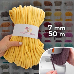 Puede incluir: Un ovillo de cordón de macramé amarillo brillante, de 7 mm de grosor y 50 m de largo, sostenido en una mano. El cordón está envuelto con una etiqueta blanca con el logotipo "macranova". Otros colores de cordón de macramé son visibles en el fondo.