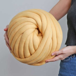May include: A large ball of yellow yarn made from soft, thick cotton. The yarn is tightly wound and has a smooth, even texture.