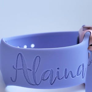 Könnte beinhalten: Ein lilafarbenes Silikon-Armband für die Apple Watch mit dem eingravierten Namen "Alaina".