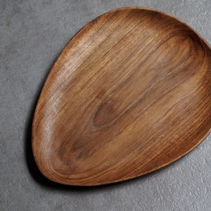 May include: A wooden serving tray with a natural wood finish and an oval shape.