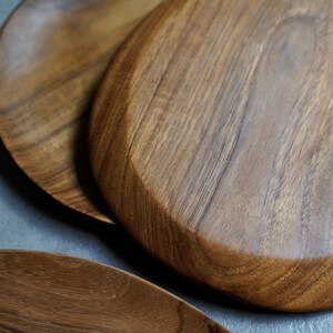 May include: Three wooden serving platters in various shapes and sizes. The platters are made of dark brown wood with a natural grain pattern.