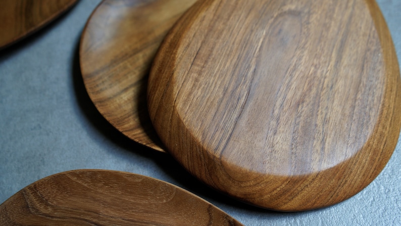 May include: Three wooden serving platters in various shapes and sizes. The platters are made of dark brown wood with a natural grain pattern.