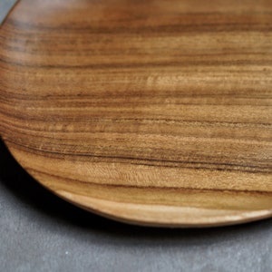 May include: A wooden serving tray with a natural wood grain finish. The tray is oval shaped and has a slightly raised edge.