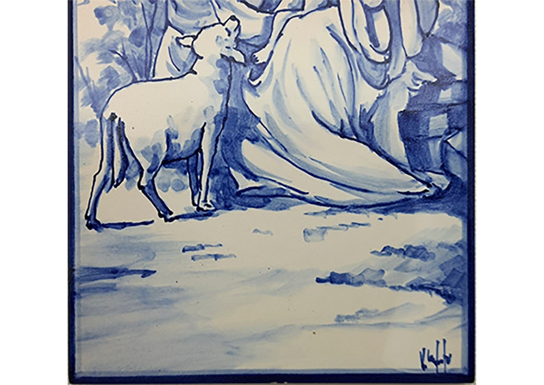 May include: A hand-painted ceramic tile featuring a woman, a child, and a lamb, all depicted in blue and white. The woman is wearing a long flowing robe and the child is sitting on her lap. The lamb is standing in front of them. The tile is bordered in blue.