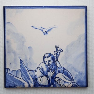 Pu&ograve; includere: Una piastrella di ceramica blu e bianca che rappresenta una scena religiosa. La piastrella mostra un uomo e una donna inginocchiati in preghiera, con una colomba che vola sopra di loro. La piastrella &egrave; dipinta in uno stile tradizionale blu e bianco.
