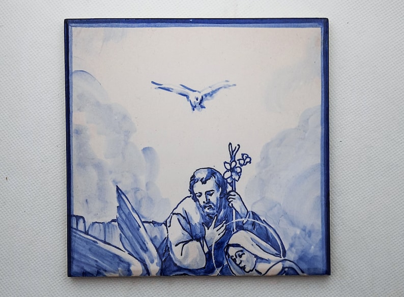Pu&ograve; includere: Una piastrella di ceramica blu e bianca che rappresenta una scena religiosa. La piastrella mostra un uomo e una donna inginocchiati in preghiera, con una colomba che vola sopra di loro. La piastrella &egrave; dipinta in uno stile tradizionale blu e bianco.
