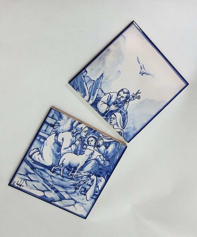 Pu&ograve; includere: Due piastrelle in ceramica blu e bianca che raffigurano una scena della Nativit&agrave;. La piastrella superiore mostra Giuseppe, Maria e una colomba che vola sopra. La piastrella inferiore mostra Maria, Giuseppe, il bambino Ges&ugrave; e un agnello.