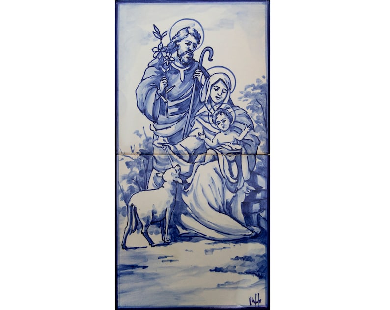 May include: A blue and white ceramic tile depicting the Holy Family. Joseph holds a staff and a sprig of olive branches. Mary holds the baby Jesus. A white lamb is in the foreground.