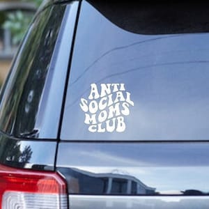 May include: A black SUV with a white vinyl sticker on the back window that says "Anti Social Moms Club" in a retro font.