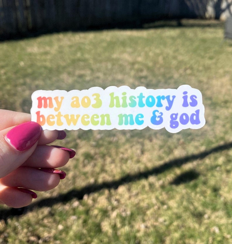 May include: A rainbow sticker with the text "my ao3 history is between me & god" on a white background.