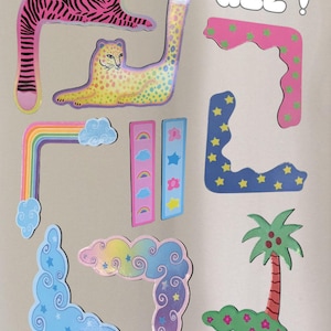 Puede incluir: Una colección de pegatinas coloridas y caprichosas con un tigre rosa, un leopardo amarillo, un arcoíris, nubes, estrellas y una palmera. La palabra "ALL!" está escrita en letras de burbujas. Ideal para decorar.