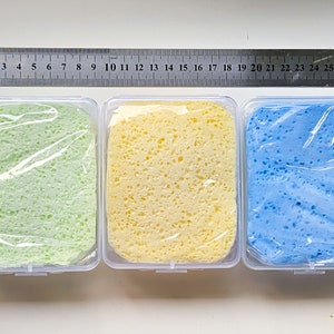 May include: Three rectangular containers with lids, each containing a different colored sponge. The sponges are light green, yellow, and light blue.