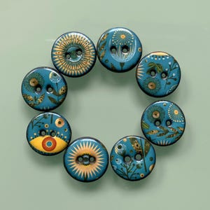 Könnte beinhalten: Ein Set aus acht runden Knöpfen in kreisförmiger Anordnung, jeweils mit einer blaugrünen Basis und komplizierten botanischen sowie sonnenstrahlenartigen Mustern in Gold, Gelb und Grün. Jeder Knopf hat zwei mittige Löcher und eine glatte Oberfläche.