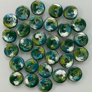 Puede incluir: Una colecci&oacute;n de 25 botones con estampado de remolino verde y blanco. Los botones son de diferentes tama&ntilde;os y formas, pero todos tienen un dise&ntilde;o similar.