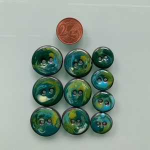 Puede incluir: Diez botones de dos agujeros con un patr&oacute;n de espiral en verde, azul y blanco.