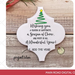 Puede incluir: Adorno de cerámica blanca con forma de árbol de Navidad con un diseño de árbol verde y el texto "Wishing you a season of happiness, a season of cheer, and most of all, a wonderful year! Add the year".
