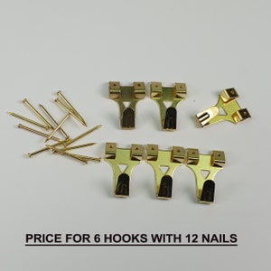 May include: Six gold-toned metal picture hooks with twelve gold-toned nails. PRICE FOR 6 HOOKS WITH 12 NAILS