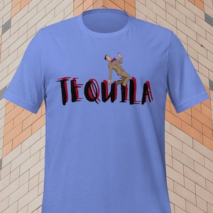 May include: A light blue t-shirt featuring the word "TEQUILA" in black and red, with an illustration of a person in a suit falling. The design is centered on the front of the shirt.