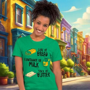 Könnte beinhalten: Ein grünes T-Shirt mit einer weißen Grafik eines Laibes Brot, einem Behälter mit Milch und einer Stange Butter. Der Text auf dem Shirt lautet "Loaf of Bread", "Container of Milk" und "Stick of Butter".