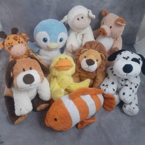 May include: A collection of plush animal toys, including a giraffe, penguin, sheep, pig, dog, duck, lion, dalmatian, and clownfish. The toys are made of soft materials and feature various colors and designs, perfect for children.
