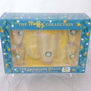 May include: A blue box with a yellow background contains a clear pitcher and three glasses with a cartoon cat design. The box says "The Muffy Collection" and "The Lemonade Stand Pitcher and Glasses 5¢ a glass".
