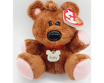 May include: A brown plush bear toy with a black nose, pink paws, and a red collar. The bear has a tag that says "Original Beanie Babies" and a white tag that says "Pooky".