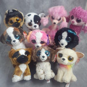 May include: A collection of plush dog toys in various breeds and colors. The toys feature large, glittery eyes and soft, textured fur. Breeds include a Dalmatian, poodle, and chihuahua. Each toy has a unique design and color scheme.