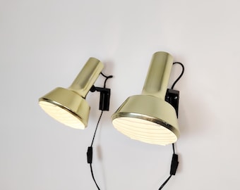 May include: Two gold-colored wall-mounted lamps with black adjustable arms and white ribbed shades.