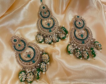 May include: A set of green and gold earrings and a matching tikka. The earrings have a circular design with green stones and pearls. The tikka has a similar design with a chain.