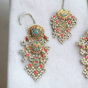 May include: A pair of gold earrings with intricate designs, featuring turquoise and pink stones, and pearl accents.