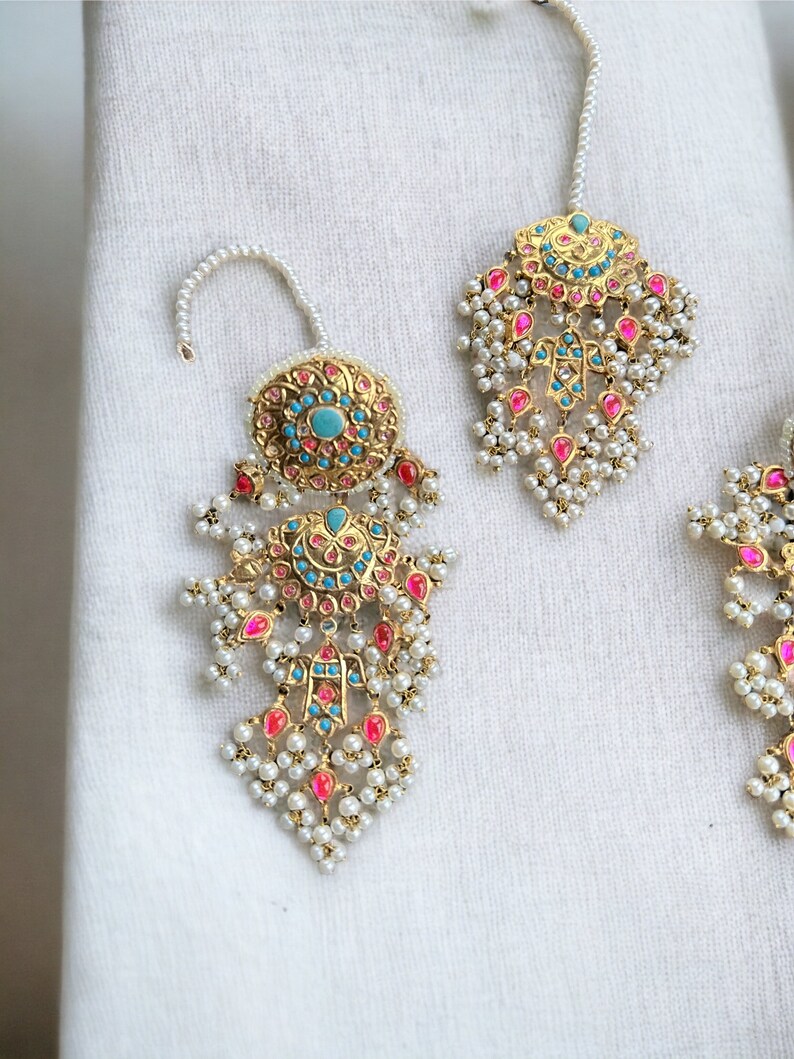 May include: A pair of gold earrings with intricate designs, featuring turquoise and pink stones, and pearl accents.