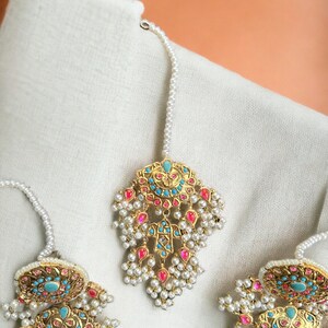 May include: A set of three gold-tone earrings with turquoise and pink stones, pearl accents, and a dangling design.