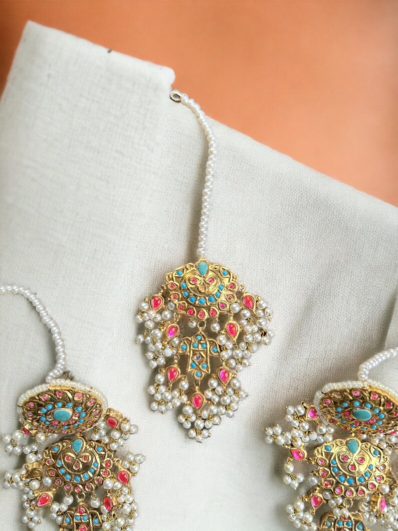 May include: A set of three gold-tone earrings with turquoise and pink stones, pearl accents, and a dangling design.