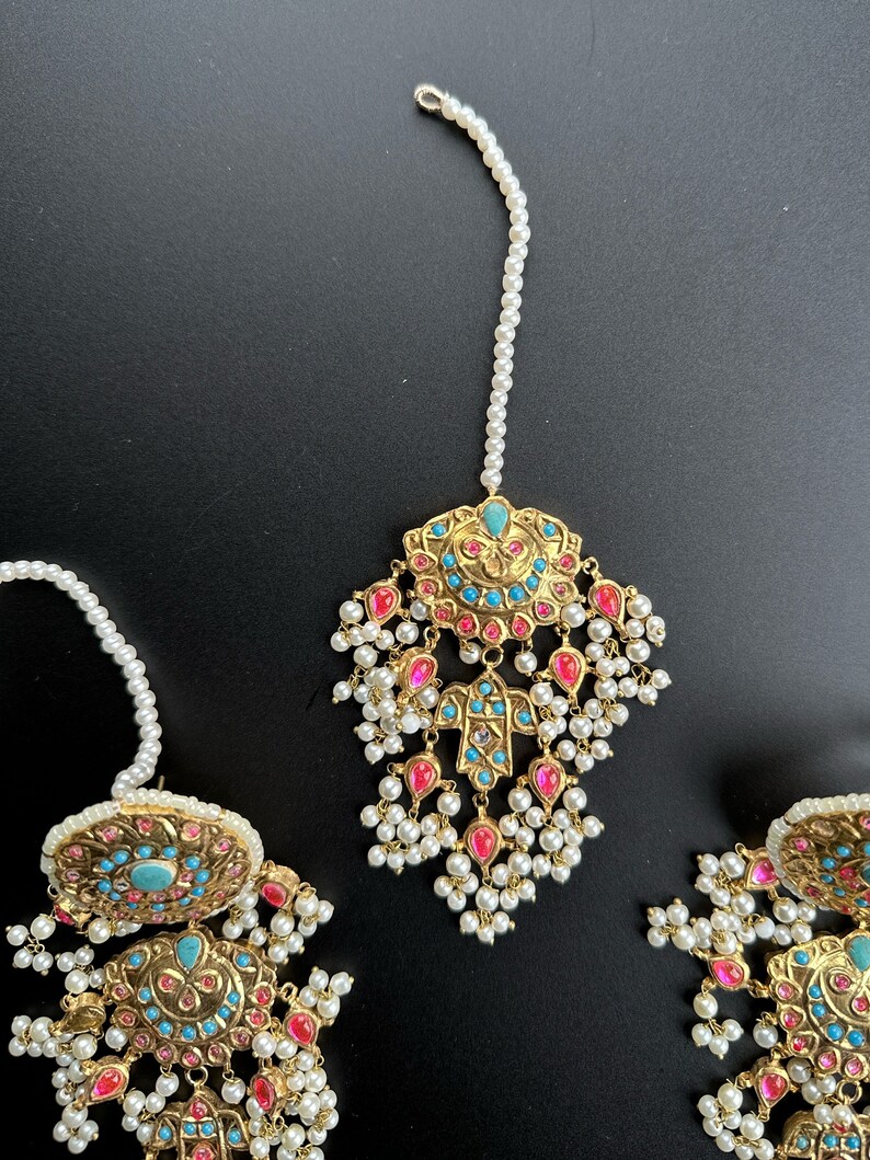 May include: A gold-tone Indian bridal tikka with turquoise and pink stones, pearl drops, and a white pearl chain.