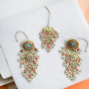 May include: A pair of gold-tone earrings with turquoise and pink stones, pearl accents, and a dangling design.