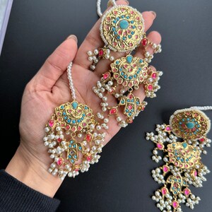 May include: A pair of gold earrings with turquoise and pink stones, pearl accents, and a dangling design.