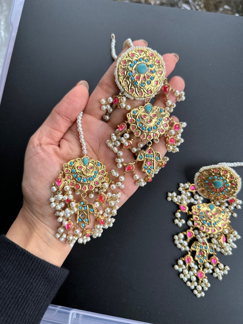May include: A pair of gold earrings with turquoise and pink stones, pearl accents, and a dangling design.
